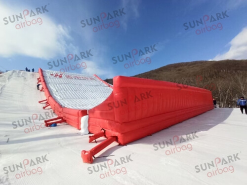 A large, Olympic-sized inflatable airbag for ski and snowboard training set up on a snowy slope