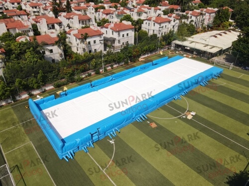 An aerial view of a large, Olympic-sized inflatable ski and snowboard airbag set up on a grassy field