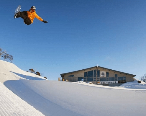 Snowboarder Valentino Guseli performing a high flying trick above a snowy jump